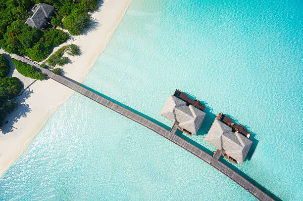 tropical hideaway from above aerial top view island with jetty and overwater villas in tropical lagoon maldive islands stock pictures, royalty-free photos & images