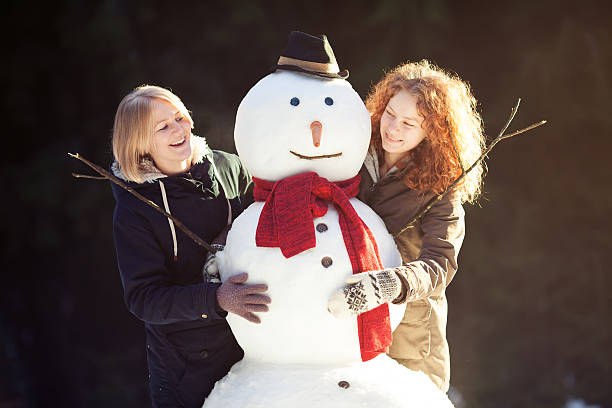 istock Two young women hugging snowman 160470242