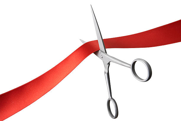 Pair of scissors cutting a red ribbon stock photo