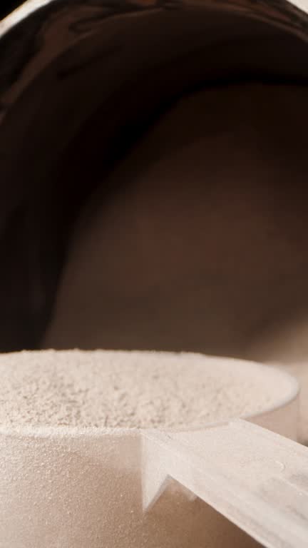 Chocolate protein powder and measuring spoon on the table, macro slider. The camera is inside the jar. Vertical video.