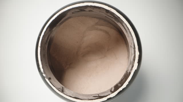 Shooting from inside a jar of chocolate protein powder, I take out a full measuring spoon from the jar. macro dolly