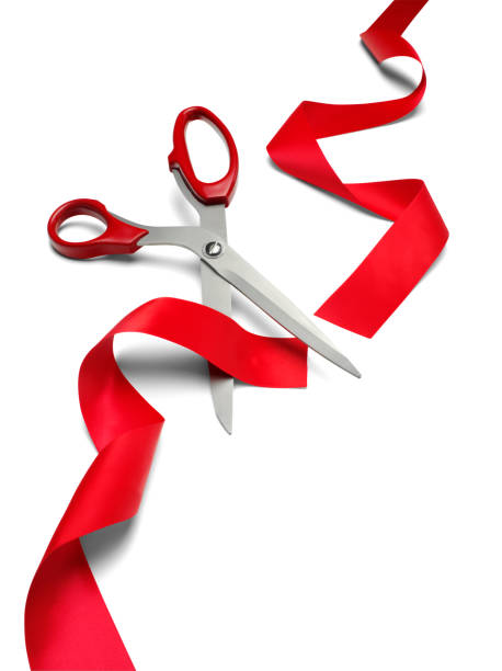 Isolated scissors cutting red ribbon on white background