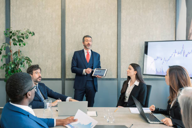 istock caucasian leader with tablet in hand coaching interested business people, giving educational workshop presentation in Concentrated employees listening to professional coach in workshop. 1604757099