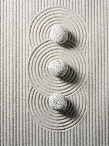 Three zen stones and circles in sand. Overhead view