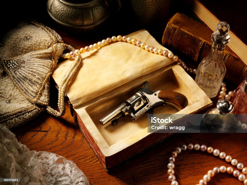 Vintage Themed Image Vintage themed image of a Edwardian gun, snuff bottle and pearls on a old wooden table. Murder Mystery Game Stock Photo