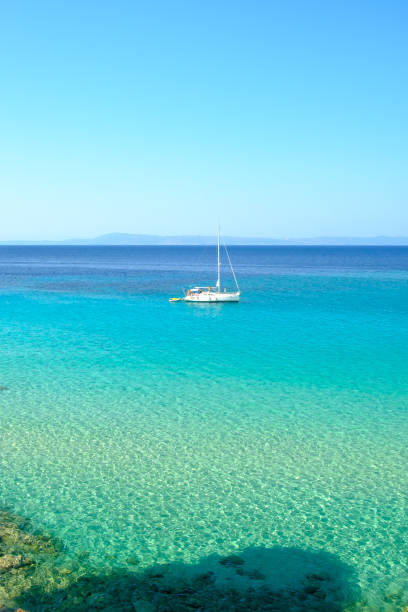 Kavourotrypes, Greece - August 14, 2017 : View of a single sailboat at the wonderful turquoise see-through beach of Kavourotrypes Chalkidiki Greece