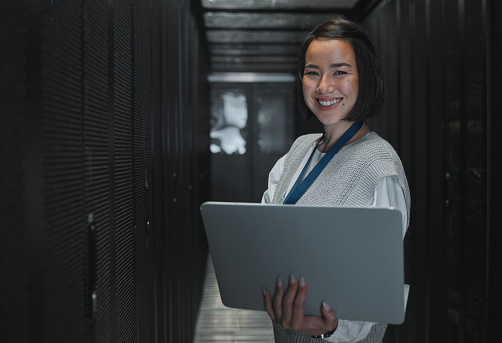 Woman with laptop, server room and information technology, smile in portrait with engineer and datacenter Software update, cybersecurity and network with Asian female setting up firewall and database