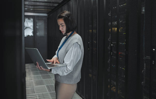 istock Server room, laptop and technician woman for data center management, system update and cyber security. Focus, serious and inspection of asian electrician, engineering or programmer person typing code 1604795581