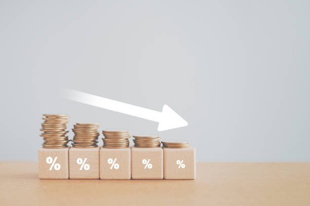 istock Coins stacking on wooden cube block with white down arrow and difference size percentage for  financial recession crisis, interest rate decline, investment reduce, risk management concept 1604799358