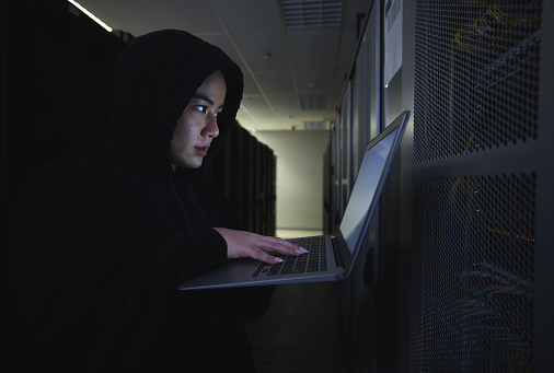 Hacker, server room and woman computer coding, data center crime and ransomware of cyberpunk in dark. Laptop hacking, person or thief in cybersecurity, information technology and criminal programmer
