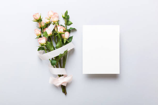 istock Greeting holiday card mockup with fresh roses on colored table background, mock up with copy space for design 1604820291