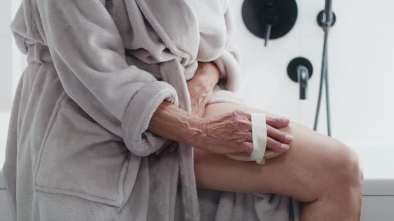 Close up of unrecognizable senior woman doing peeling of her legs in the domestic bathroom. Shot with RED helium camera in 8K.