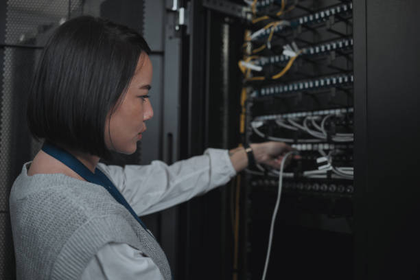 istock Asian woman, technician and server room for cabling, networking or system maintenance at office. Female engineer plugging wire for cable service, power or data security in admin or network management 1604832087