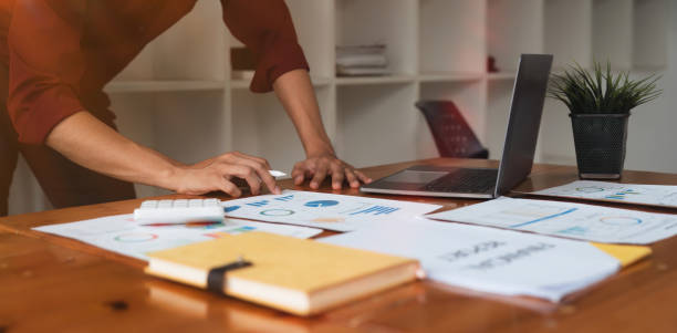 istock Asian Business man using laptop computer and working at office with calculator document on desk, doing planning analyzing the financial report, business plan investment 1604834777