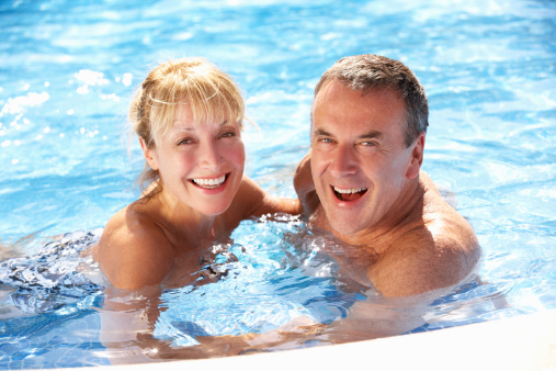 Senior Couple Having Fun In Swimming Pool Smiling To Camera