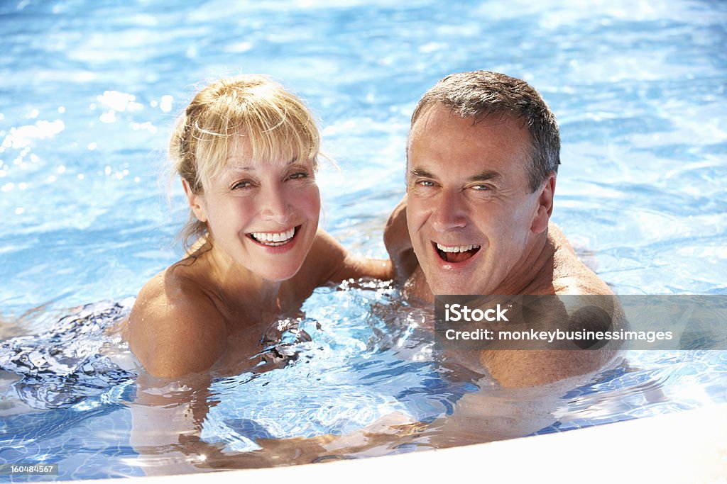 Senior couple in the pool smiling together Senior Couple Having Fun In Swimming Pool Smiling To Camera Swimming Pool Stock Photo