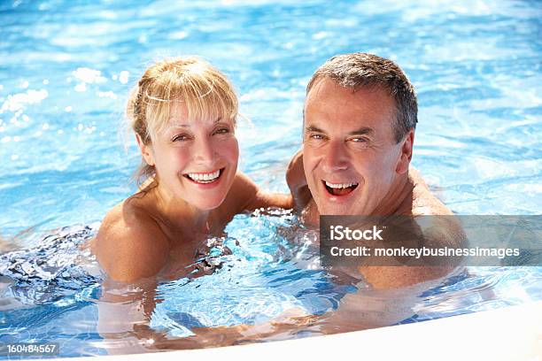 Senior Couple In The Pool Smiling Together Stock Photo - Download Image Now - Swimming Pool, Senior Couple, Senior Adult