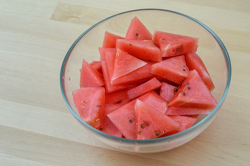 Watermelon cut into triangles in a glass bowl, top view, closeup