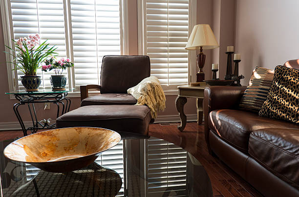 A stylish modern living room with brown leather furniture, glass tables and interesting accents.
