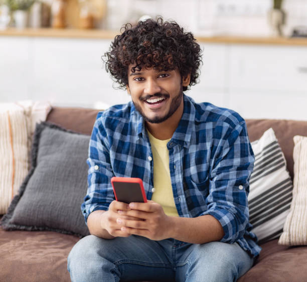 istock Happy young man with using mobile phone at home 1604884824