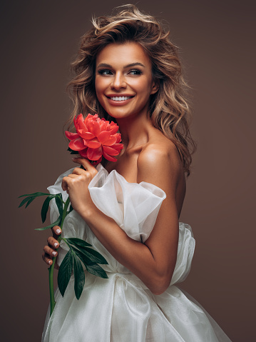 Beautiful emotional woman with perfect dress and make-up holding a flower