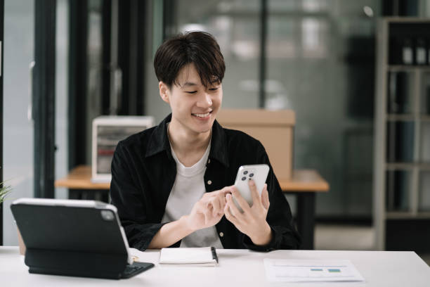 istock Happy young man looking at cellphone screen, reading message, or email, communicating distantly with client or playing games from computer work in modern office. 1604896816
