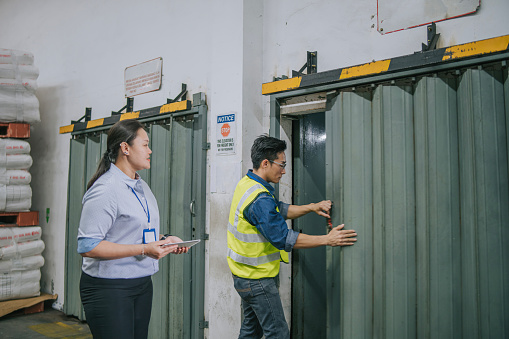 Asian chinese warehouse worker closing elevator door