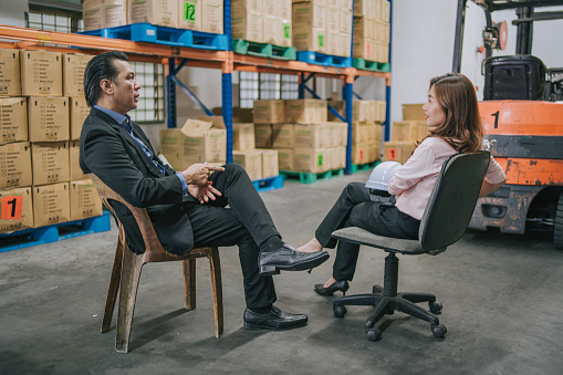 Asian businessman talking to warehouse female foreperson in warehouse