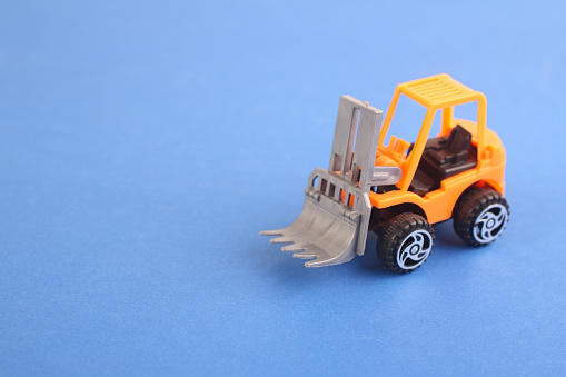 Toy forklift loader isolated on blue background. moving service and distribution products. Delivery production. Logistics and industrial concept