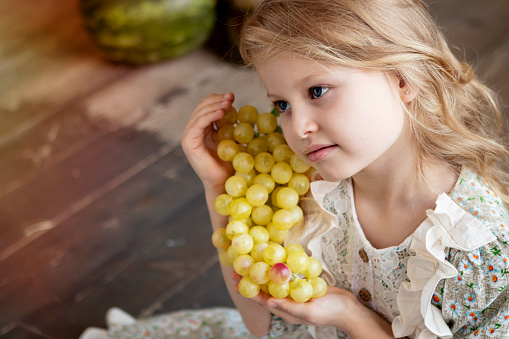 girl with long blond hair with a grape harvest in her hands