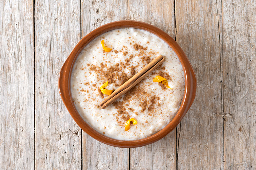 Arroz con leche. Rice pudding with cinnamon in clay bowl on wooden table