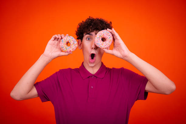 istock Young attractive guy eats pink donuts. Delicious breakfast and good vibes. 1604963735