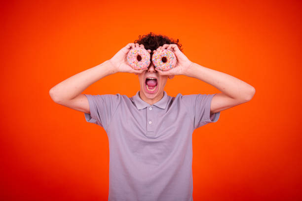 istock Young attractive guy eats pink donuts. Delicious breakfast and good vibes. 1604967481