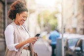 Phone, city and business woman walking and travel in a town typing on social media, online or internet. Connection, smile and happy African person texting a contact via email, web or mobile app