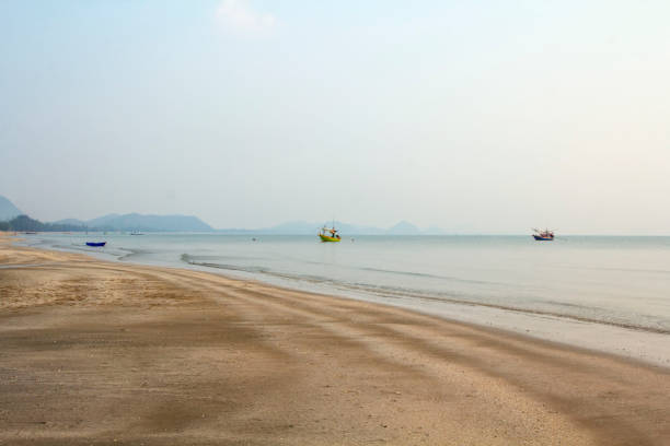 istock The beach is quiet in the evening, the sky is light blue, no people, suitable for resting, walking, exercising, see the fishing boat parked in the sea, near the longest shore. 1605015391