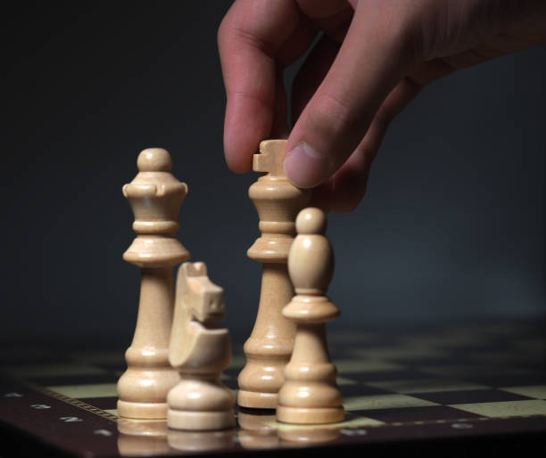 istock Hand on chessboard and pieces flying. Cloudy background 1605038359