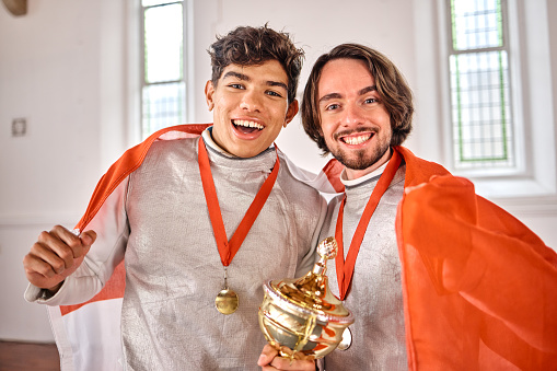 Flag, fencing and portrait of men with trophy for winning competition, challenge and sports match. Canada, sword fighting and excited male athletes celebrate with prize for games and tournament