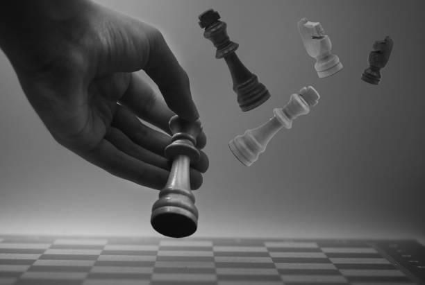 istock Hand on chessboard and pieces flying. Cloudy background 1605038930
