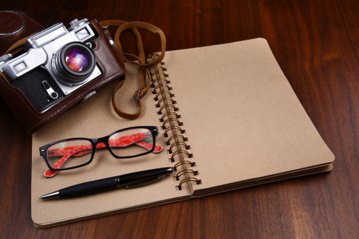 Camera, glasses and pen on notebook. Old paper note book, free space for write some comment.