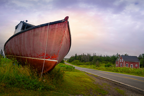 An old fishing boat or trawler parked on the roadside in the 300-year-old village of Gabarus, Cape Breton, Nova Scotia, Canada