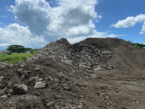 Huge pile of rocks and ground soil dumped into agricultural field for concrete overpass construction.