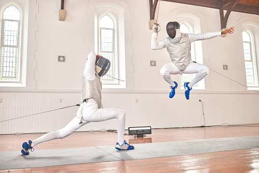 Jump, fencing and people with sword to fight in training, exercise or workout in a hall. Martial arts, sports and fencers or men with mask and costume for fitness, competition or target in swordplay