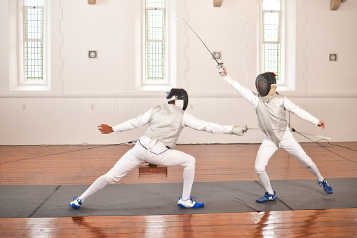 People, training and fight in fencing competition, duel or combat with martial arts fighter and athlete with a sword and weapon. Warrior, blade and couple in creative fight, exercise or fitness