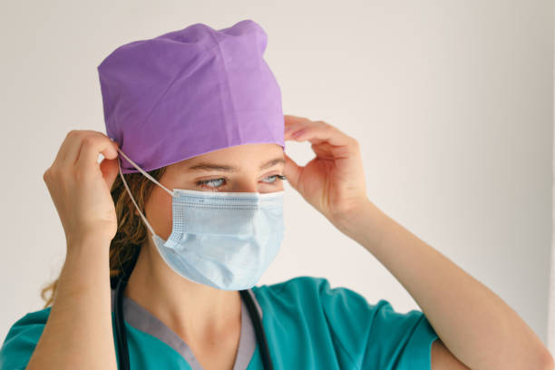 istock Young woman in scrubs with mask 1605061379