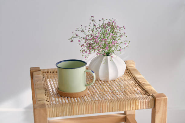 istock Mug and vase with flowers on wicker table 1605063839