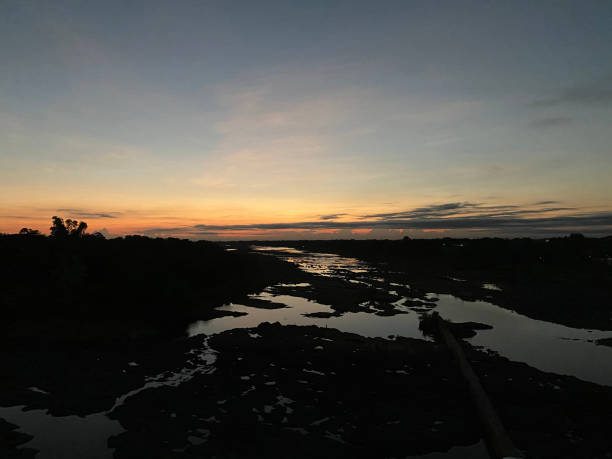 istock Sunrise over a drying up huge river. Silhouettes 1605064963