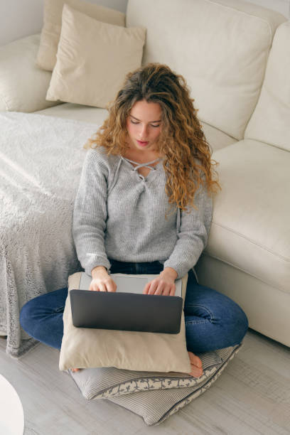 istock Young woman with notebook sitting on pillow 1605068268