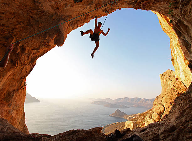 rock alpinista ao pôr do sol - climbing men sea cliff imagens e fotografias de stock