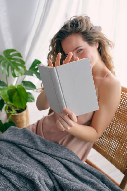 istock Young woman reading book on wicker chair 1605073726