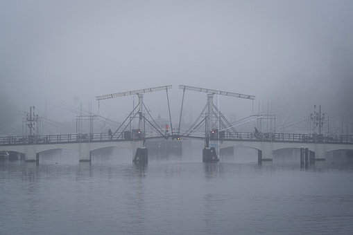 Amsterdam, Netherlands – November 27, 2022: Amsterdam, Netherlands - November 27 2022: The world famous skinny bridge in Amsterdam, shrouded in fog on an autumn morning in November.